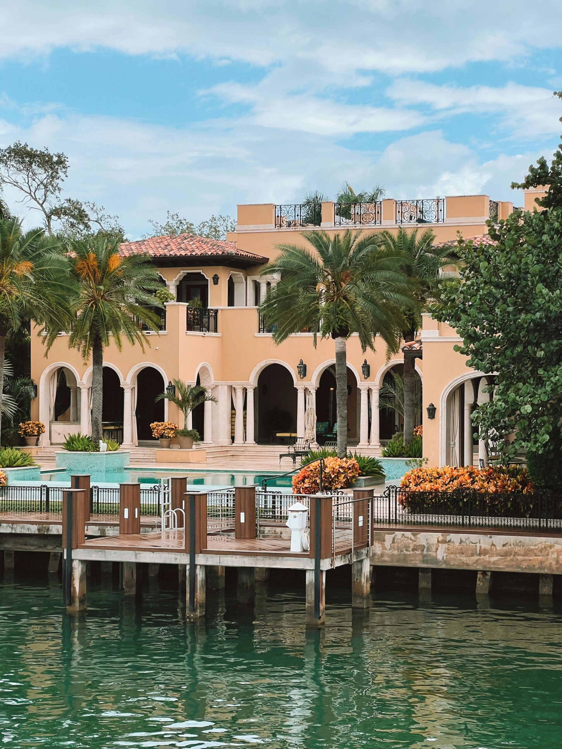 Elegant Mediterranean style villa with lush palm trees and waterfront view.