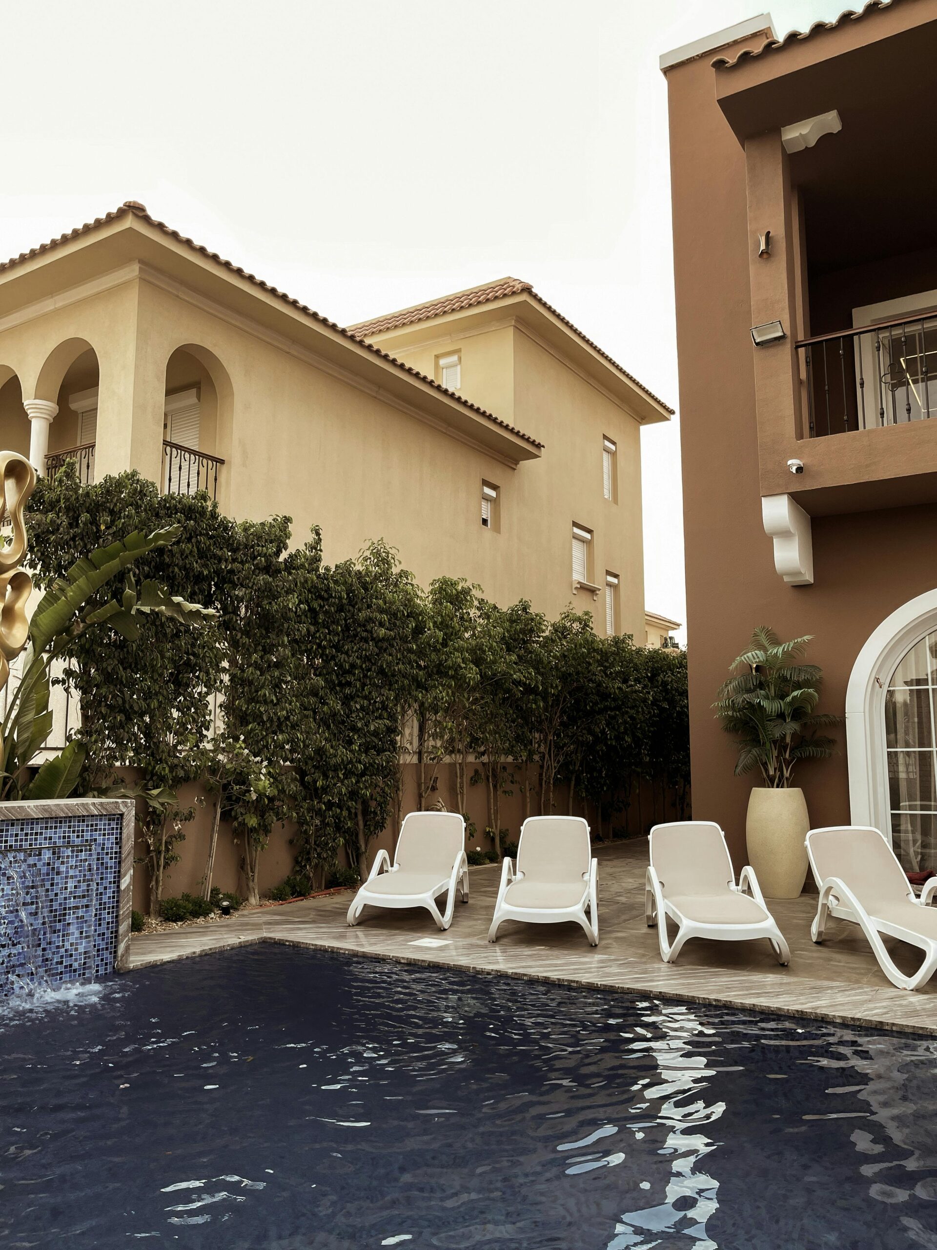 Inviting poolside scene with loungers and Mediterranean-style architecture under a clear sky.